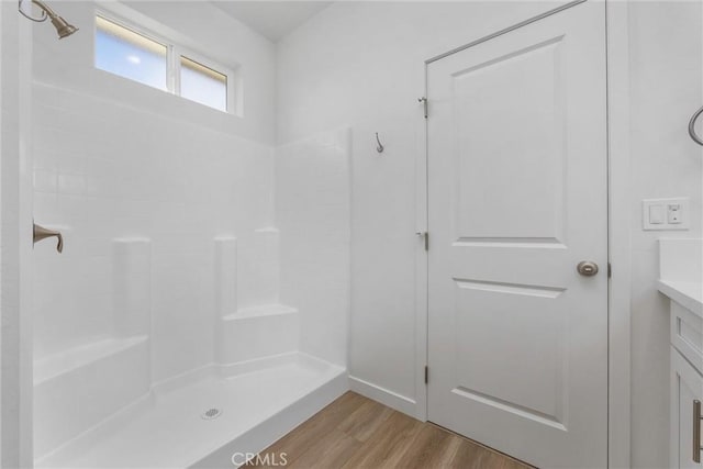 bathroom with a shower, wood finished floors, and vanity