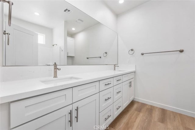 full bath with double vanity, wood finished floors, a sink, and visible vents