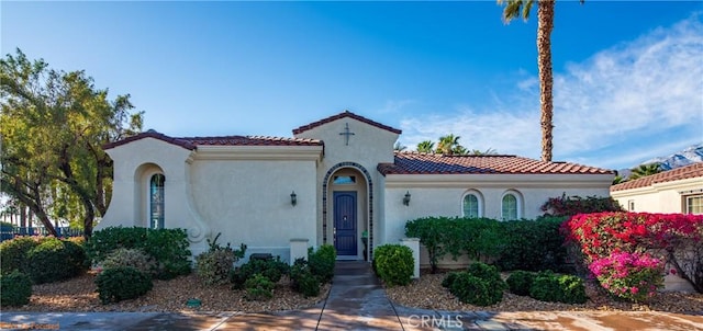 mediterranean / spanish home featuring a tile roof and stucco siding