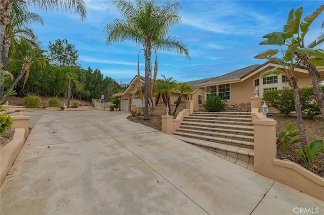 view of front of property with a garage, concrete driveway, and stucco siding