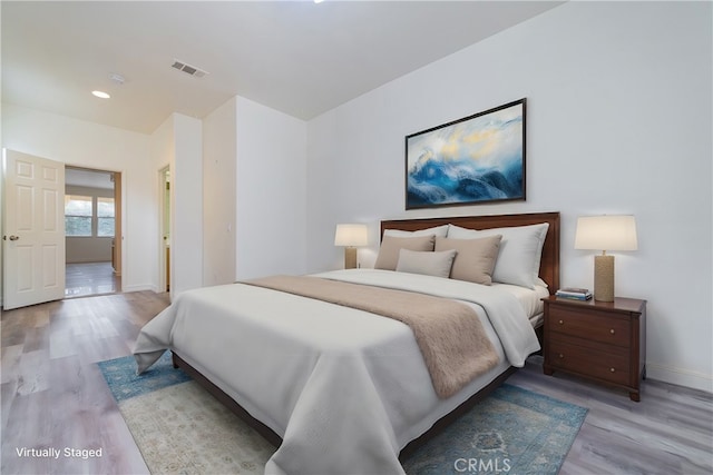 bedroom featuring light wood-style flooring, visible vents, and baseboards