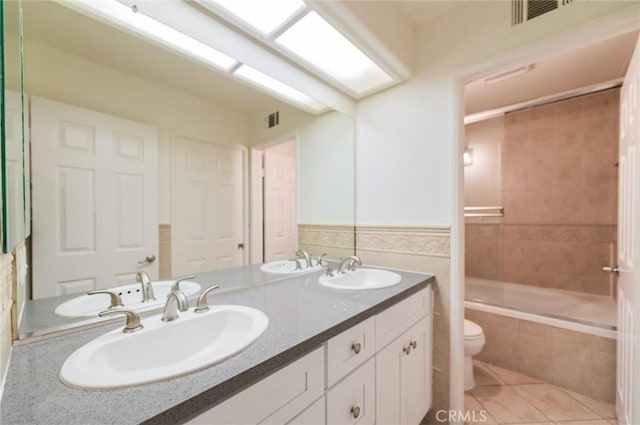 bathroom with double vanity, a sink, toilet, and tile patterned floors