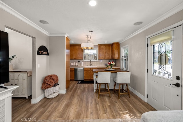 kitchen with a sink, dishwasher, brown cabinetry, and crown molding