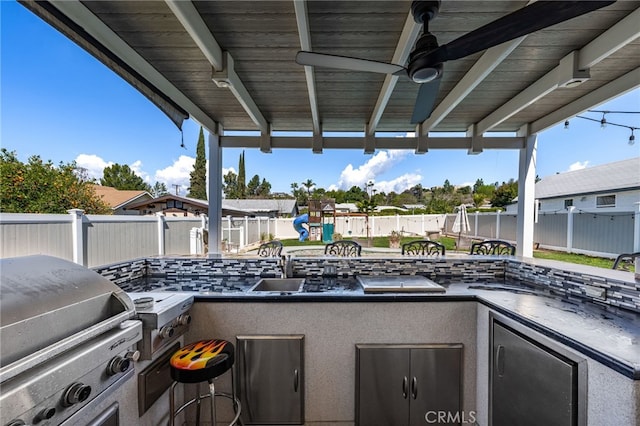 view of patio featuring a sink, an outdoor kitchen, a fenced backyard, a grill, and ceiling fan