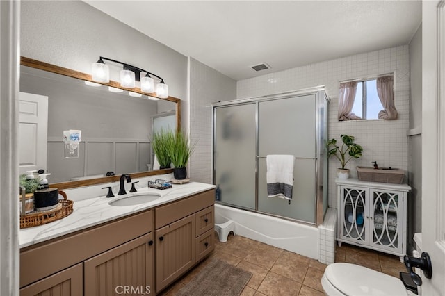 bathroom featuring tile patterned floors, visible vents, toilet, bath / shower combo with glass door, and vanity