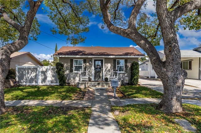 bungalow featuring a front yard and fence