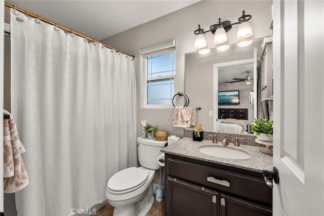 full bath featuring ceiling fan, toilet, vanity, a textured wall, and ensuite bath