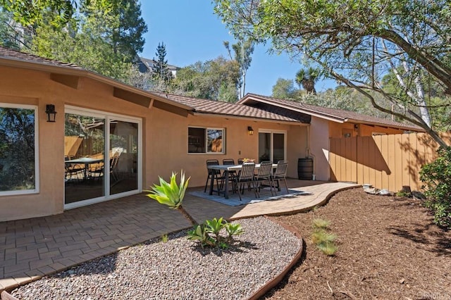 rear view of property featuring a patio area, stucco siding, and fence