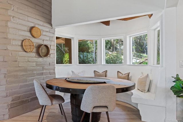 dining room featuring wood finished floors and brick wall