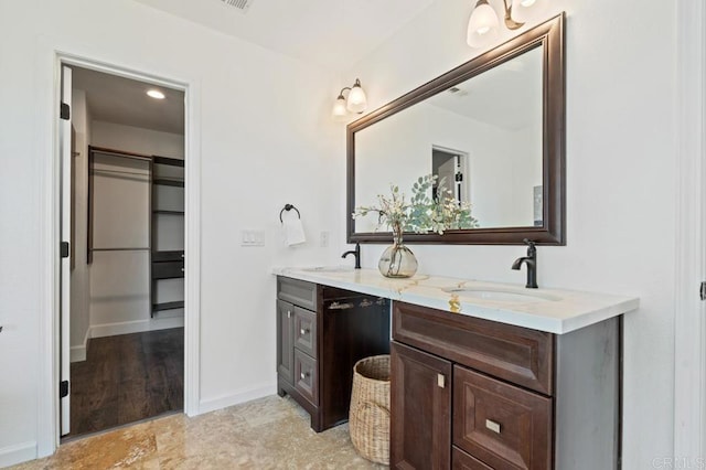 bathroom featuring a sink, baseboards, and double vanity