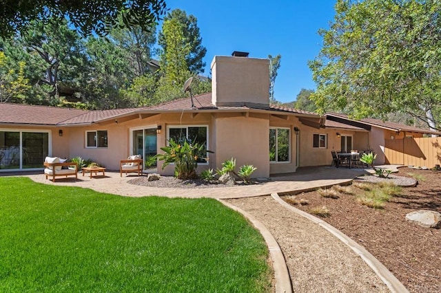 rear view of property with stucco siding, fence, a yard, a chimney, and a patio area