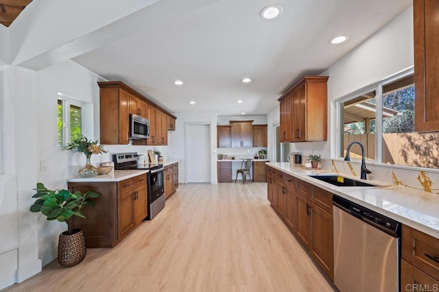 kitchen with light wood-style flooring, a sink, recessed lighting, appliances with stainless steel finishes, and light countertops