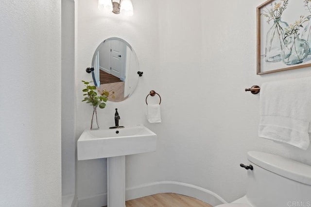 bathroom with baseboards, toilet, and wood finished floors