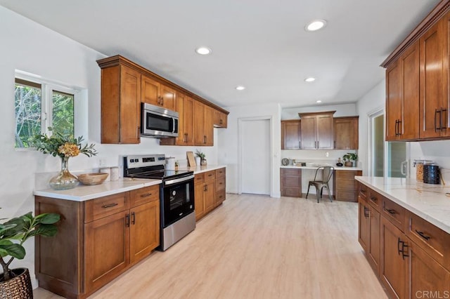 kitchen featuring recessed lighting, light wood-style floors, brown cabinets, and stainless steel appliances