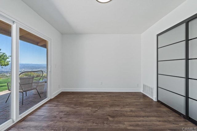 empty room featuring dark wood finished floors, baseboards, and visible vents