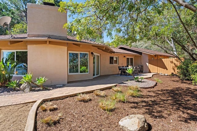 rear view of house featuring stucco siding, a patio, and fence