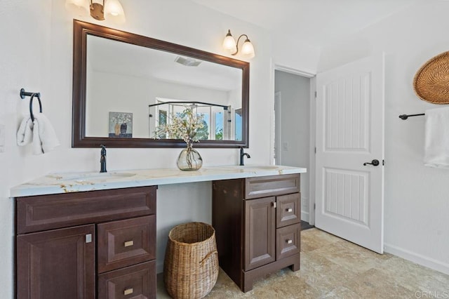 full bath with double vanity, baseboards, and a sink