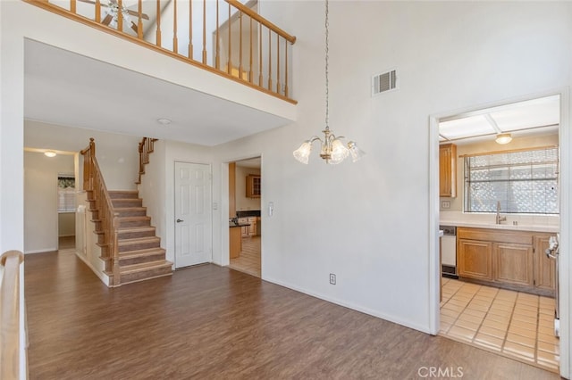 6118 Landau Pl, Quartz Hill, CA 93536 - unfurnished living room with light wood finished floors, stairs, a towering ceiling, and a chandelier