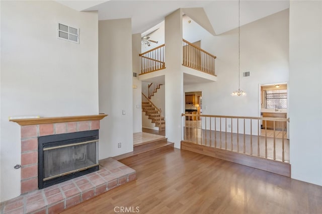 6118 Landau Pl, Quartz Hill, CA 93536 - unfurnished living room with wood finished floors, a fireplace, high vaulted ceiling, ceiling fan, and stairs