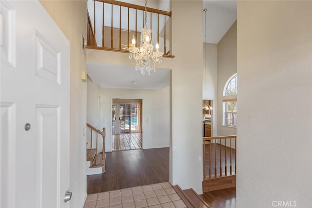 tiled foyer featuring a notable chandelier, a towering ceiling, and stairs