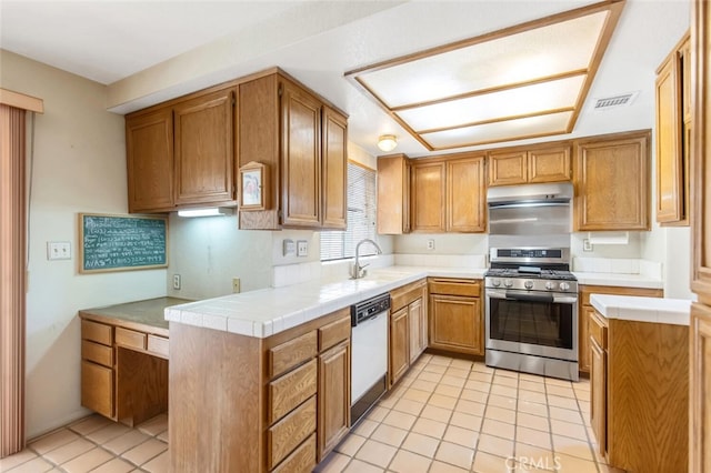 kitchen with under cabinet range hood, visible vents, dishwasher, brown cabinetry, and gas range