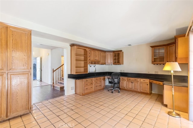 kitchen with built in desk, open shelves, visible vents, glass insert cabinets, and light tile patterned flooring