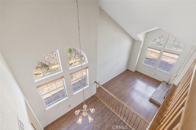 living room with high vaulted ceiling, wood finished floors, and a notable chandelier