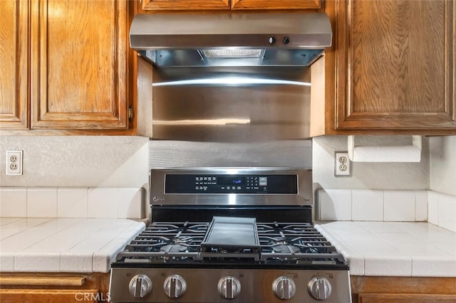 kitchen with exhaust hood, tile counters, decorative backsplash, and gas stove