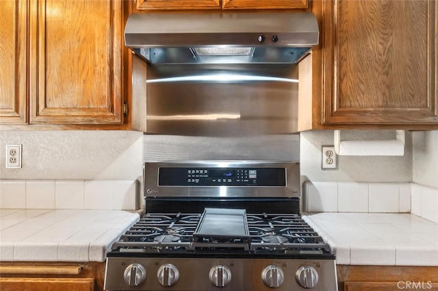 6118 Landau Pl, Quartz Hill, CA 93536 - kitchen with stainless steel gas range oven, under cabinet range hood, tile countertops, and tasteful backsplash