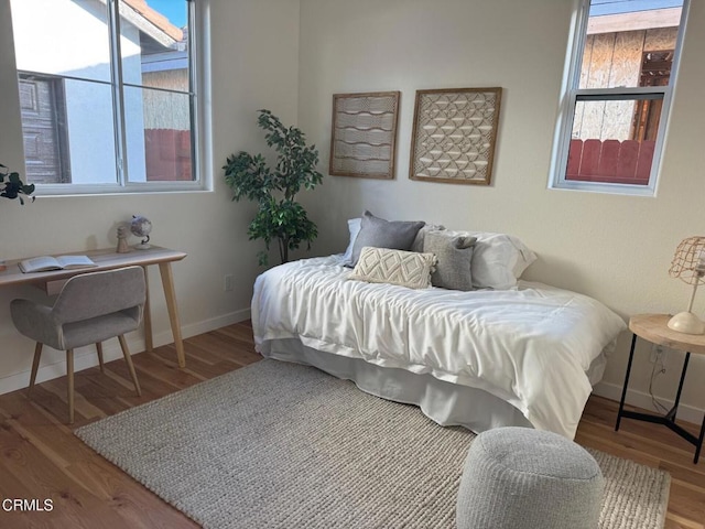 bedroom featuring multiple windows, baseboards, and wood finished floors