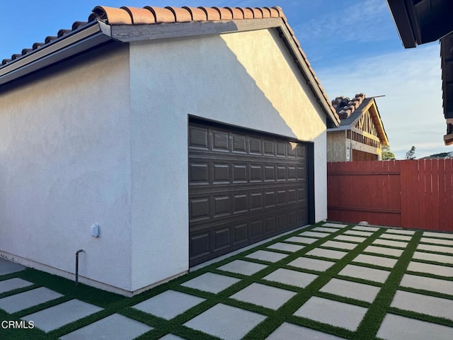 view of property exterior featuring fence, a tiled roof, and stucco siding