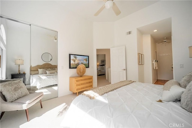 bedroom featuring visible vents, ceiling fan, a closet, a towering ceiling, and light carpet