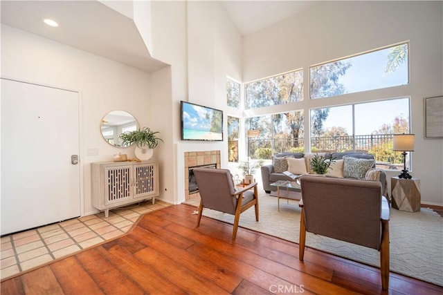 living room featuring wood finished floors, a high ceiling, and a fireplace