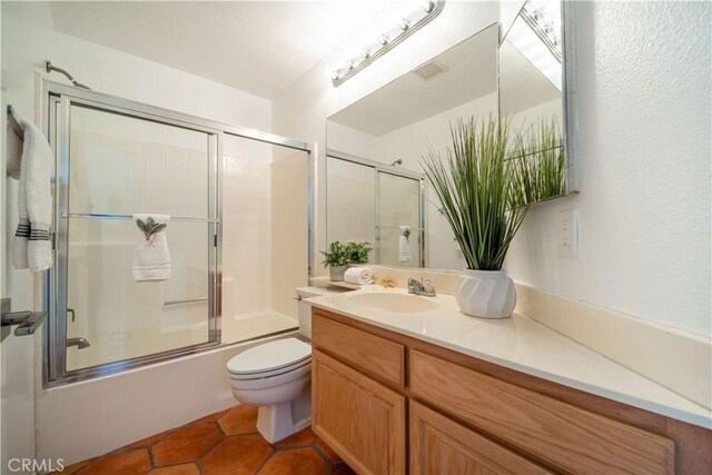 full bathroom featuring tile patterned flooring, visible vents, toilet, shower / bath combination with glass door, and vanity