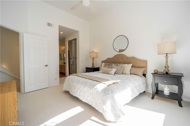 bedroom with light carpet, visible vents, ensuite bathroom, and lofted ceiling