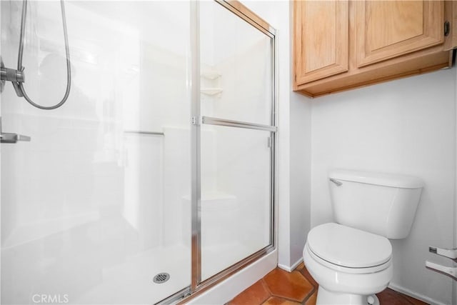 full bathroom featuring a shower stall, toilet, baseboards, and tile patterned floors