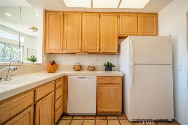 kitchen with tile counters, white appliances, and a sink