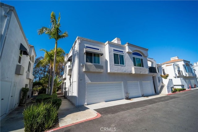 multi unit property with a chimney, a garage, and stucco siding