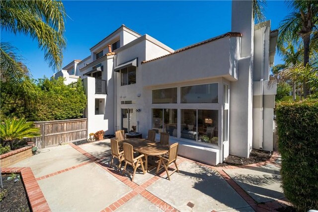 rear view of house featuring stucco siding, a patio, and outdoor dining space