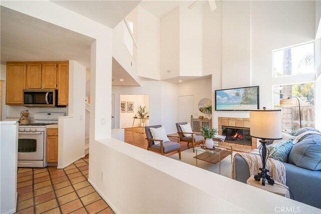 living area featuring light tile patterned floors, a towering ceiling, and a tiled fireplace