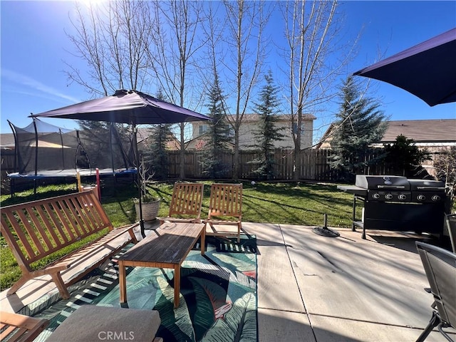 view of patio / terrace with a trampoline, a grill, and fence