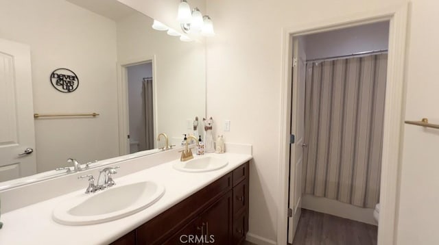 bathroom featuring double vanity, wood finished floors, a sink, and a shower with shower curtain