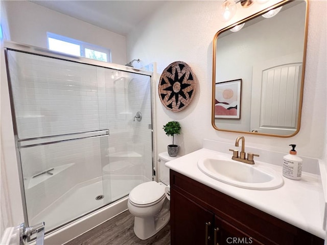 bathroom with toilet, a stall shower, and vanity