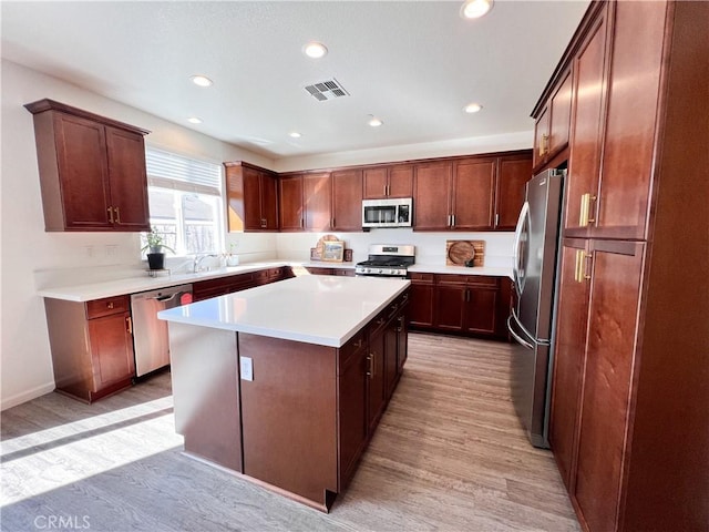 kitchen with visible vents, light wood-style flooring, appliances with stainless steel finishes, a center island, and light countertops