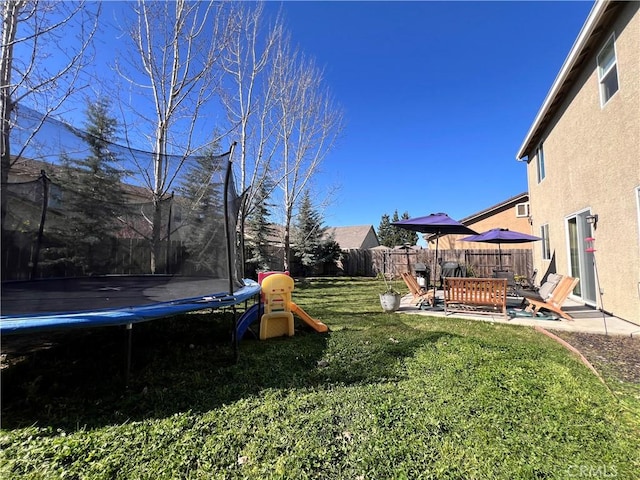 view of yard with a patio, a trampoline, and a fenced backyard