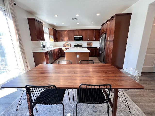 kitchen with light wood finished floors, visible vents, appliances with stainless steel finishes, and a center island