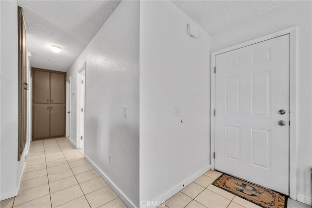 interior space with light tile patterned floors, baseboards, and a textured ceiling