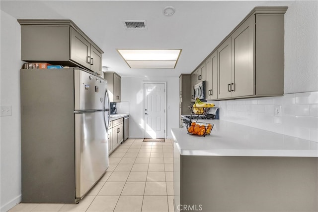 kitchen featuring light tile patterned floors, visible vents, decorative backsplash, gray cabinets, and stainless steel appliances