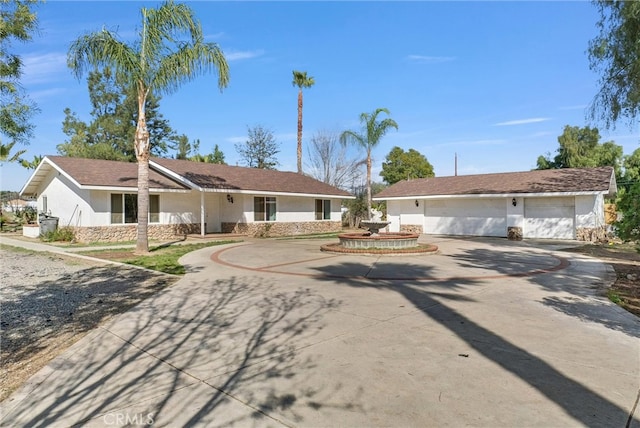 ranch-style house with a garage, driveway, and stucco siding