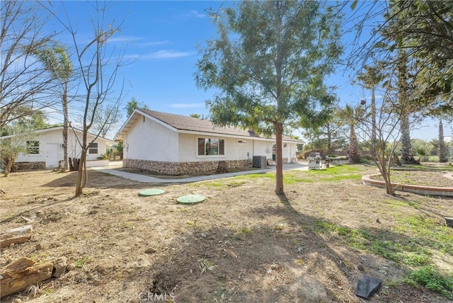 view of side of home featuring stone siding, cooling unit, and stucco siding